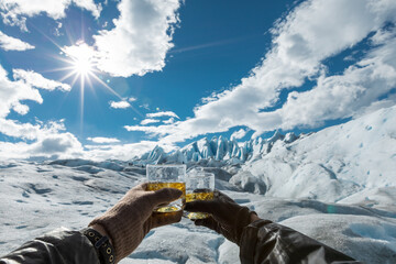 Two hands holding glasses with drinks with ice cubes from the Perito Moreno Glacier