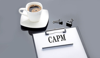 CAPM - Capital Asset Pricing Model text on the paper sheet with coffee on the black background