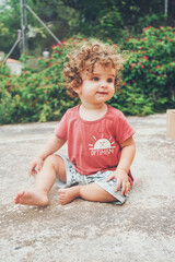 Fototapeta premium Cute toddler sit on the backyard floor
