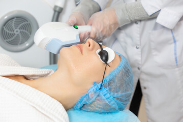 Woman client in a beauty salon is undergoing a photo rejuvenation procedure of alignment skin tone, removing traces of pigmentation. Starting the rejuvenation process by producing own collagen