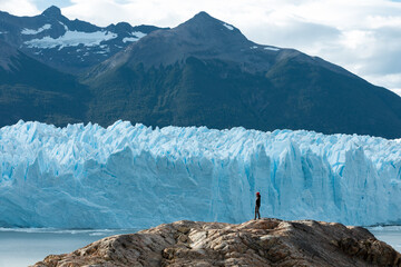 A woman standing on the rock formation and looking at the Perito Moreno Glacier
