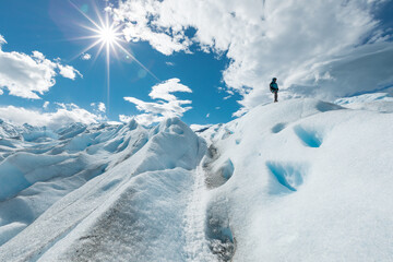 A man standing on top of the snowy ice formation of the Perito Moreno Glacier