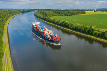 Container ships on the Kiel Canal and windmill on the background. © snapshotfreddy