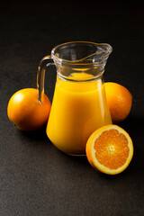 Fresh orange juice with oranges on a dark background