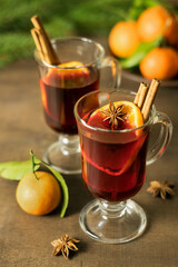 Christmas mulled wine with spices on a wooden table with spruce branches and tangerines. Traditional hot winter drink. The concept of the New Year and Christmas.