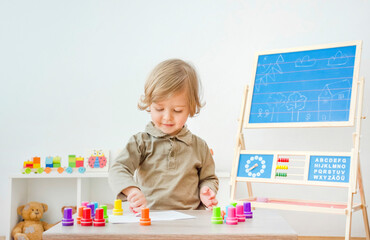 Cute little child having fun at home playing with colorful stamps on paper. Indoor activity for...
