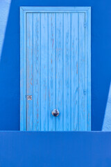 Picturesque vintage blue wooden door over a blue wall. Outdoor