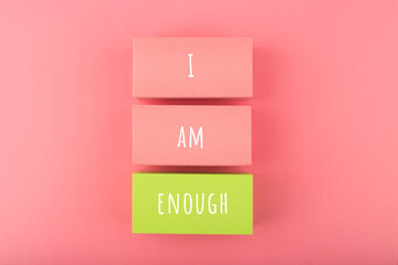 I am enough concept with words written on colorful rectangles against bright pink background. Self...