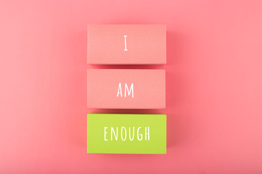 I am enough concept with words written on colorful rectangles against bright pink background. Self love concept