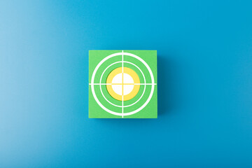 Goal or target symbol on green cube in the middle of blue background. Concept of scoring and setting personal or business goal