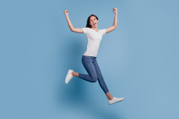 Fototapeta na wymiar Portrait of funky girlish active lady jump run raise fists scream goal on blue background