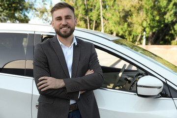 Handsome young driver near modern car on city street