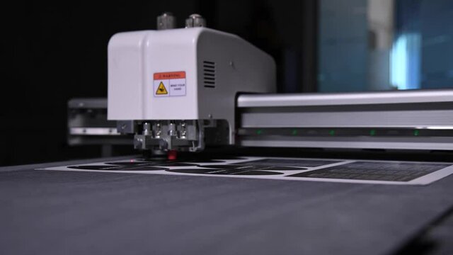 industrial plotter cuts a template on a cardboard packaging for products. real time shallow depth of field. Live camera