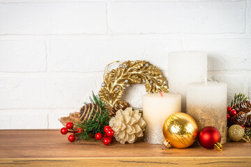 Christmas decorations indoor. Shelf with candles, fir tree branches and decorations at white wall background. © nadianb