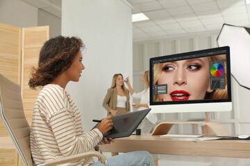 Professional African American retoucher working with graphic tablet at desk in photo studio