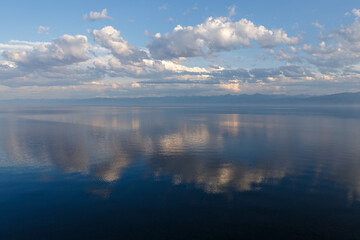 Lake Baikal in the evening. Ripples on the water surface and beautiful clouds. The clouds are reflected in the water.