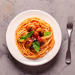 Spaghetti with meatballs and tomato sauce on a stone background