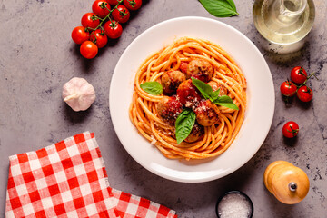 Spaghetti with meatballs and tomato sauce on a stone background