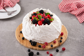 Delicious Pavlova cake with meringue topped and fresh berries on gray stone