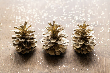 natural golden cones on a wooden table with gold spangles in the shape of stars, among fir branches