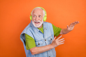 Photo of funny funky retired man wear vintage jeans waistcoat listening music headphones dancing smiling isolated orange color background