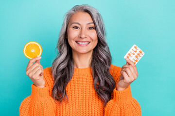 Photo of cheerful senior lady hold tablets treatment orange fruit advertise isolated over teal color background