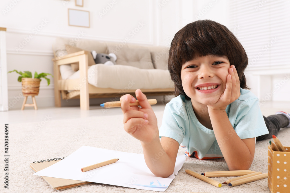 Sticker Cute little boy drawing with pencils on floor at home