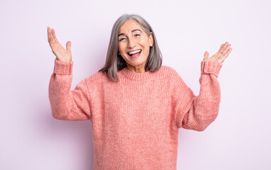 senior pretty woman feeling happy, amazed, lucky and surprised, celebrating victory with both hands...