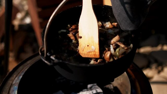 Mushrooms and onions are fried in a pan over a fire in the field
