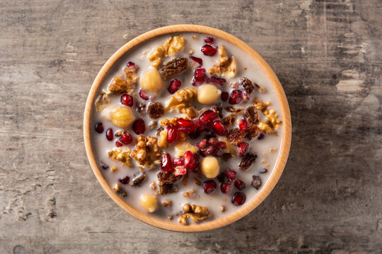 Traditional Turkish Noah's pudding in bowl on wooden table. Top view
