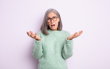 senior pretty woman feeling extremely shocked and surprised, anxious and panicking, with a stressed...
