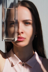 Conceptual surreal portrait Caucasian woman looking through a vase of water