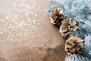 natural golden cones on a wooden table with gold spangles in the shape of stars, among fir branches