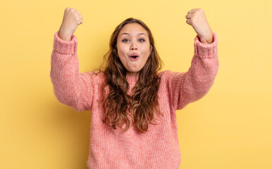 hispanic pretty woman celebrating an unbelievable success like a winner, looking excited and happy...