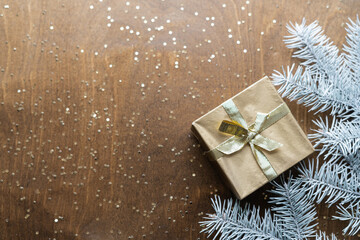 a golden gift box on a wooden table with gold spangles in the shape of stars, among the fir branches