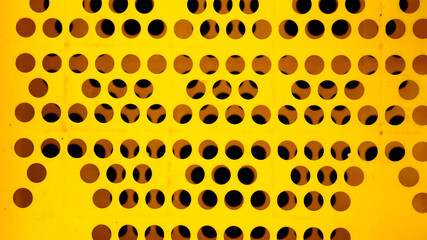 Yellow plastic surface has a black hole pattern
