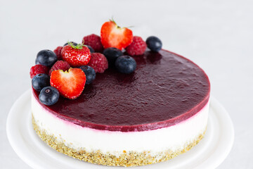Raw vegan mousse cake with berries on a light background. Sugar, gluten, lactose free.