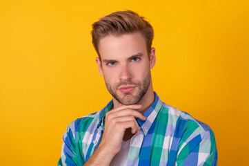 Portrait of serious handsome guy think with thoughtful face yellow background, thinking