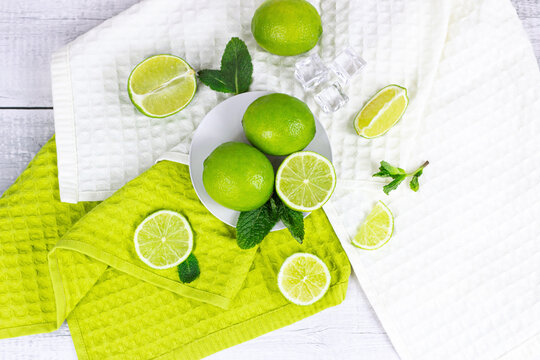 Top view of fresh green juicy limes and lime slices with mint leaves in the kitchen on light background.