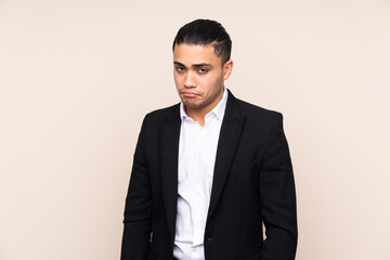 Asian business man isolated on beige background sad