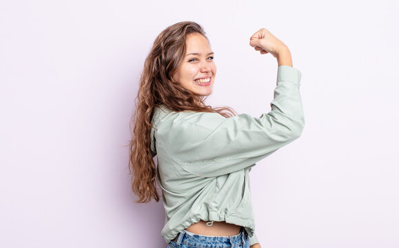 hispanic pretty woman feeling happy, satisfied and powerful, flexing fit and muscular biceps, looking strong after the gym