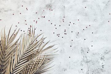 Shiny palm leaf on beton wall. Abstract frame background with copy space. Flat lay glitter confetti