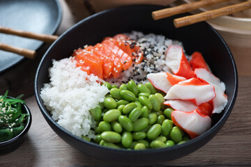 Poke with salmon, crab meat, edamame beans and daikon served in a black bowl, middle closeup, studio shot