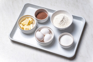 Baking ingredients in bowls: flour, eggs, sugar, butter. White background.