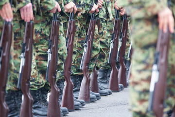 Fototapeta na wymiar Soldiers in boots and a rifle.Soldiers stand in row. Gun in hand. Army, Military Boots lines in camouflage uniforms