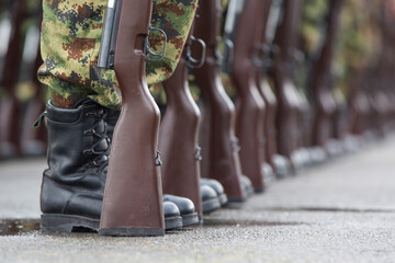 Soldiers in boots and a rifle.Soldiers stand in row. Gun in hand. Army, Military Boots lines in camouflage uniforms