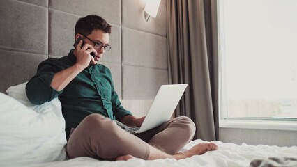 Man working at home on laptop and talking on the phone