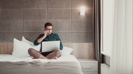 Man working at home on laptop and talking on the phone