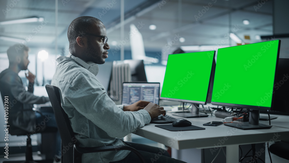 Aufkleber Multi-Ethnic Office: Black IT Programmer Working on Computer with Green Screen Chroma Key Display. Male Software Engineer Developing App, Program, Video Game. Terminal with Code Language.