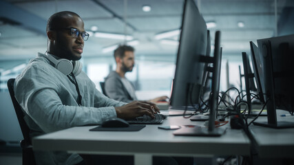 Diverse Office: Black IT Programmer Working on Desktop Computer. Male Specialist Creating...